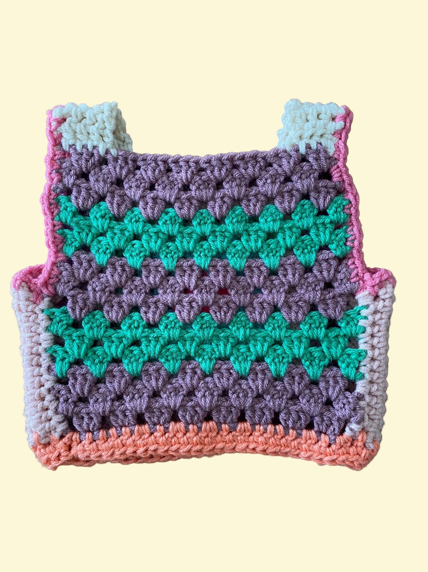 Crocheted vest with a colorful pattern on a wooden surface
