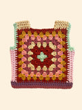 A handmade crocheted granny square vest with shoulder straps, featuring a multicolor pattern of pink, yellow, brown, and purple squares 