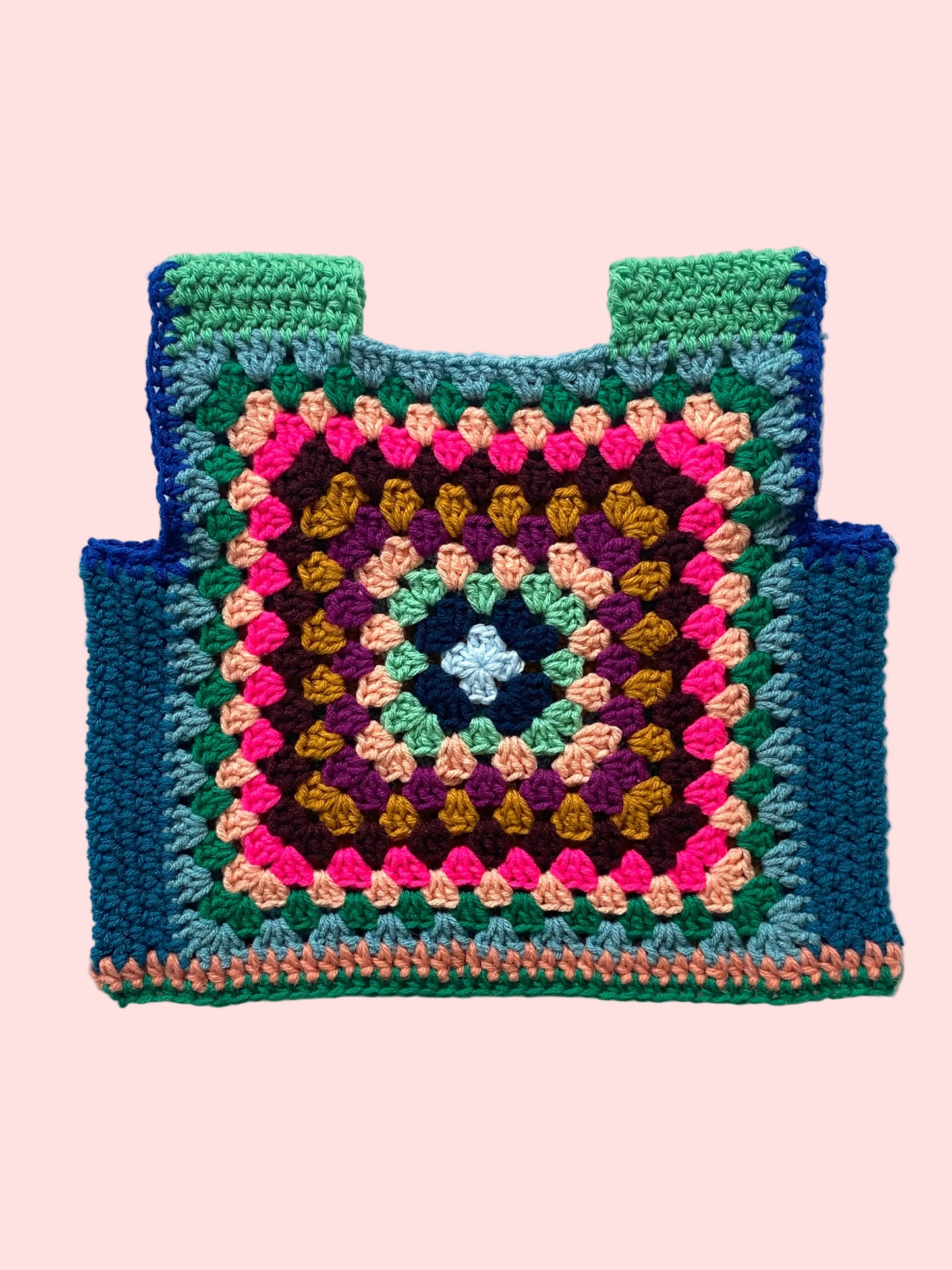 Colorful crocheted granny square vest on a white background