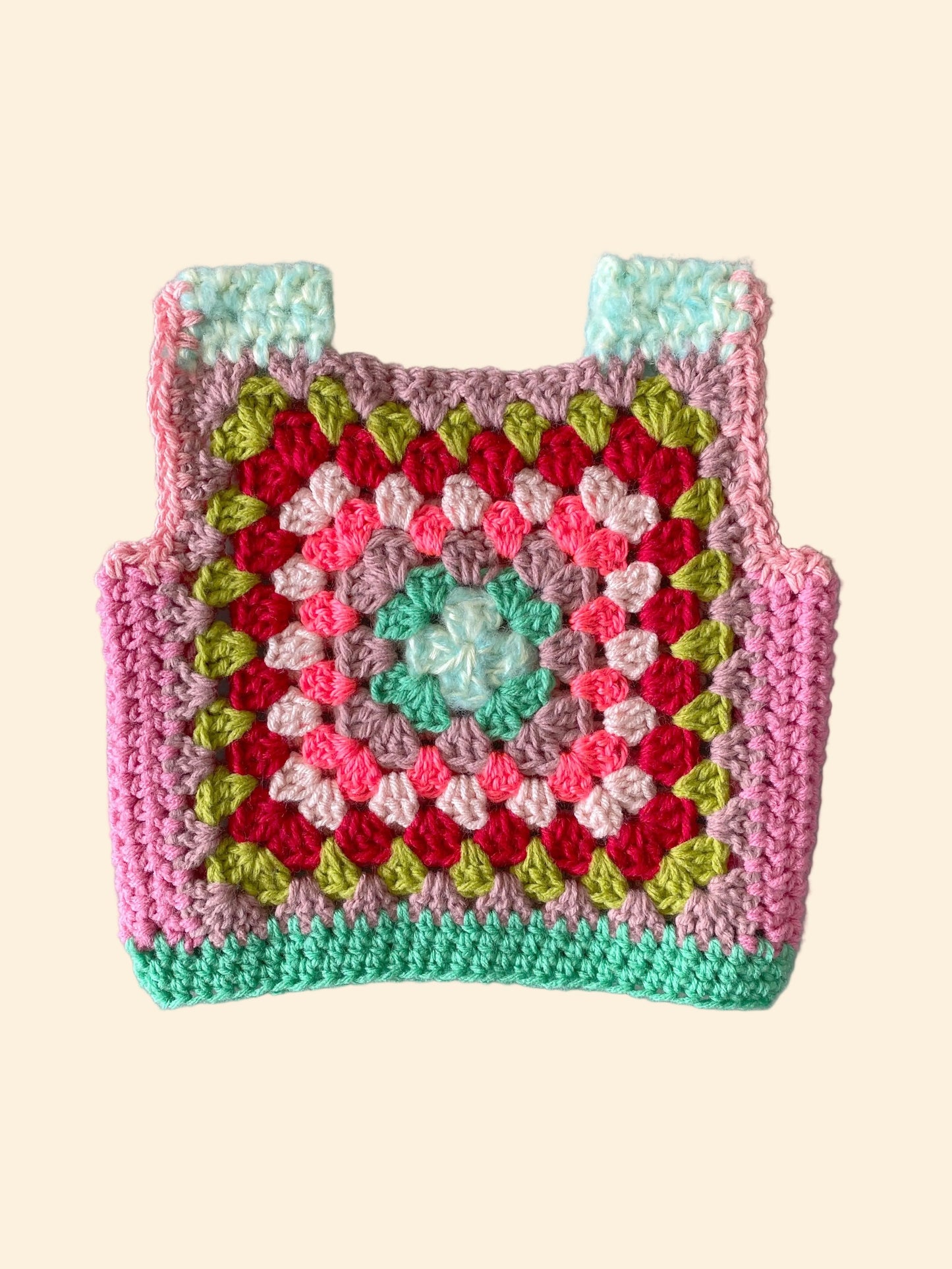 Colorful crocheted child vest with a geometric pattern on a white background