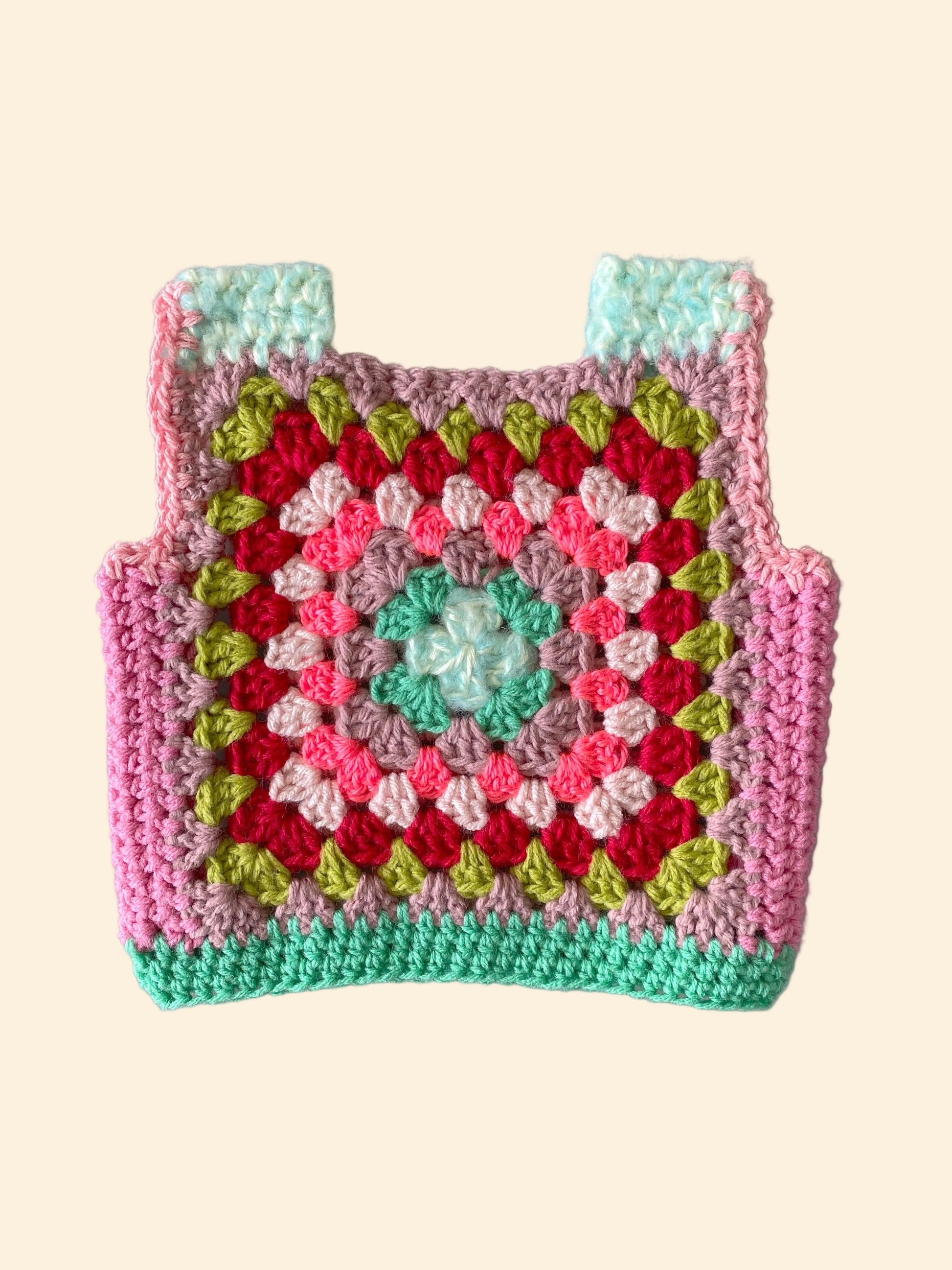 Colorful crocheted child vest with a geometric pattern on a white background
