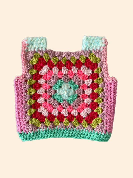 Colorful crocheted child vest with a geometric pattern on a white background