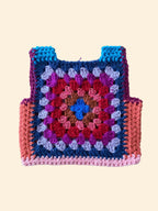 Crocheted granny square vest with multicolor pattern on a wooden surface