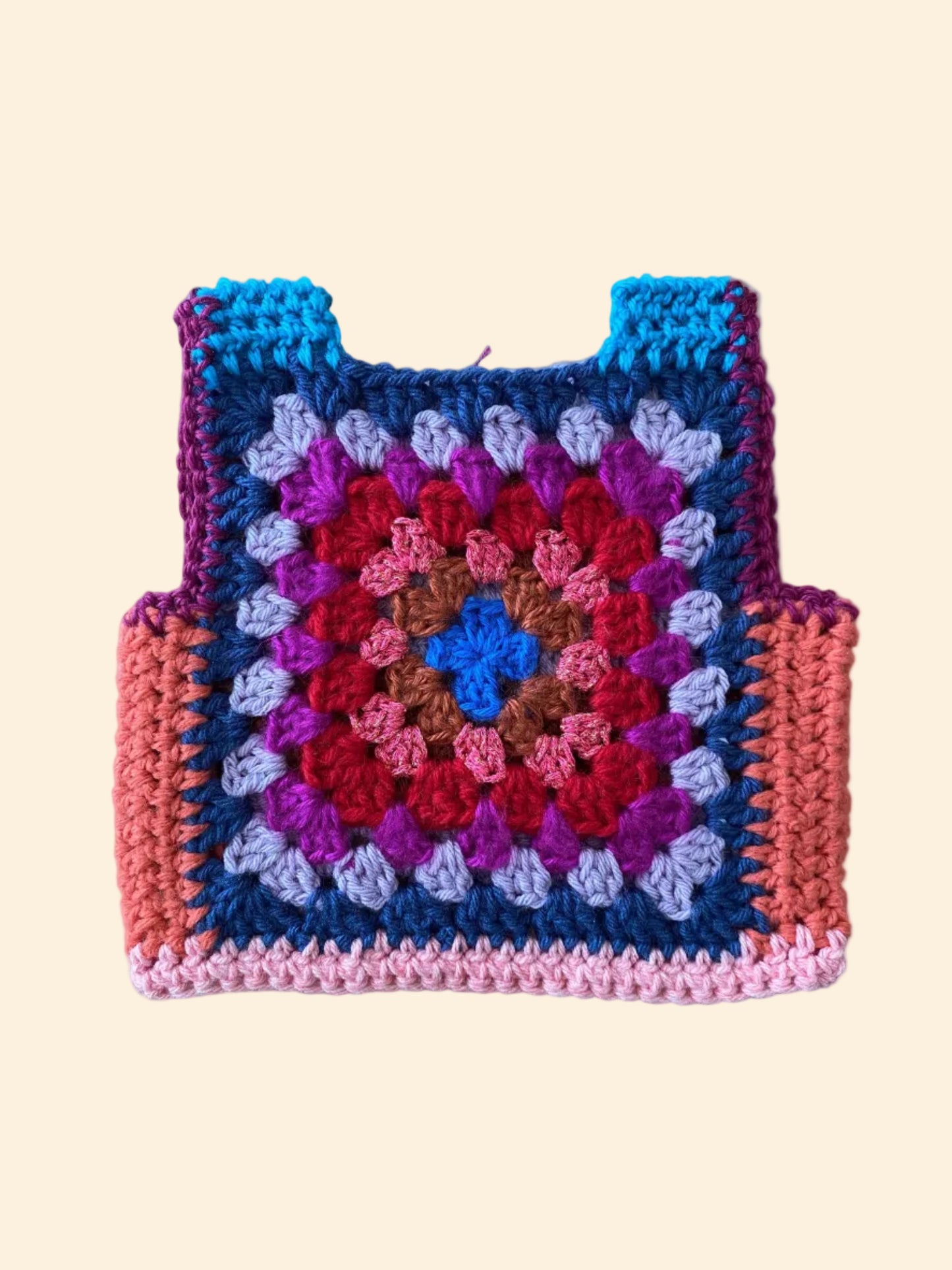 Crocheted granny square vest with multicolor pattern on a wooden surface