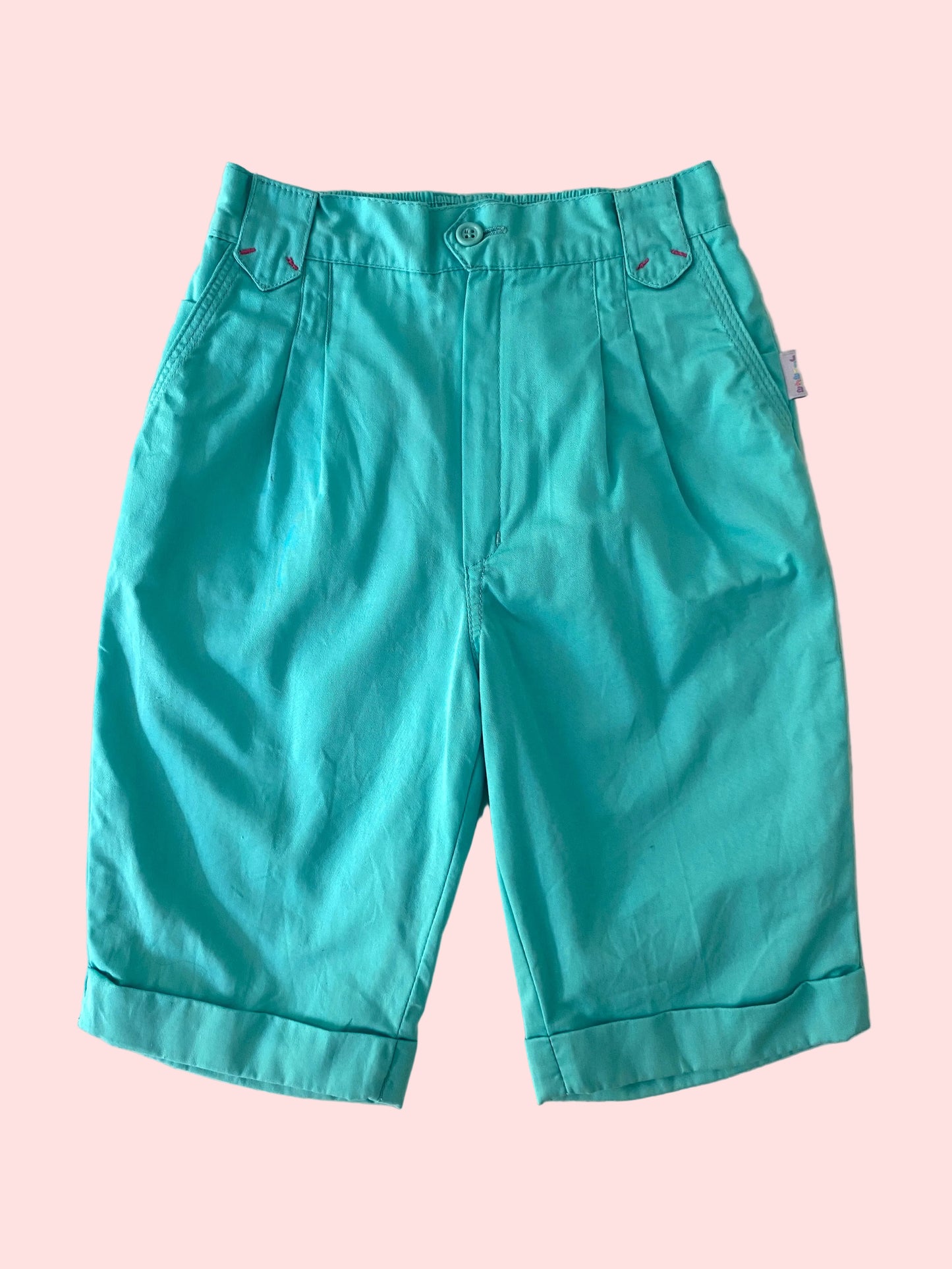 Teal capri pants on a textured white background