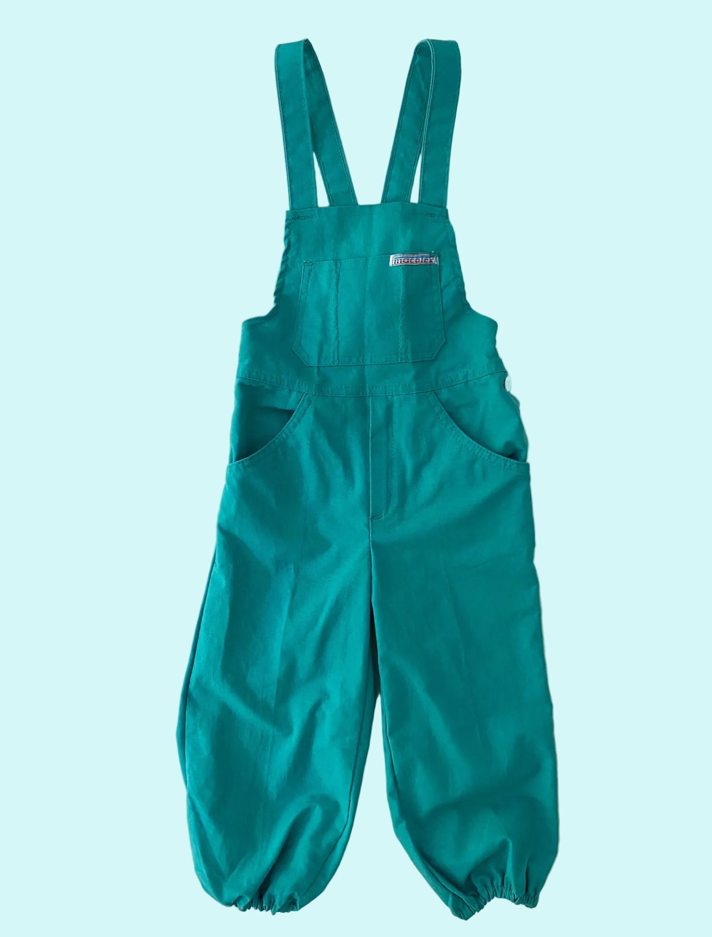 Teal bib overalls on a textured white background