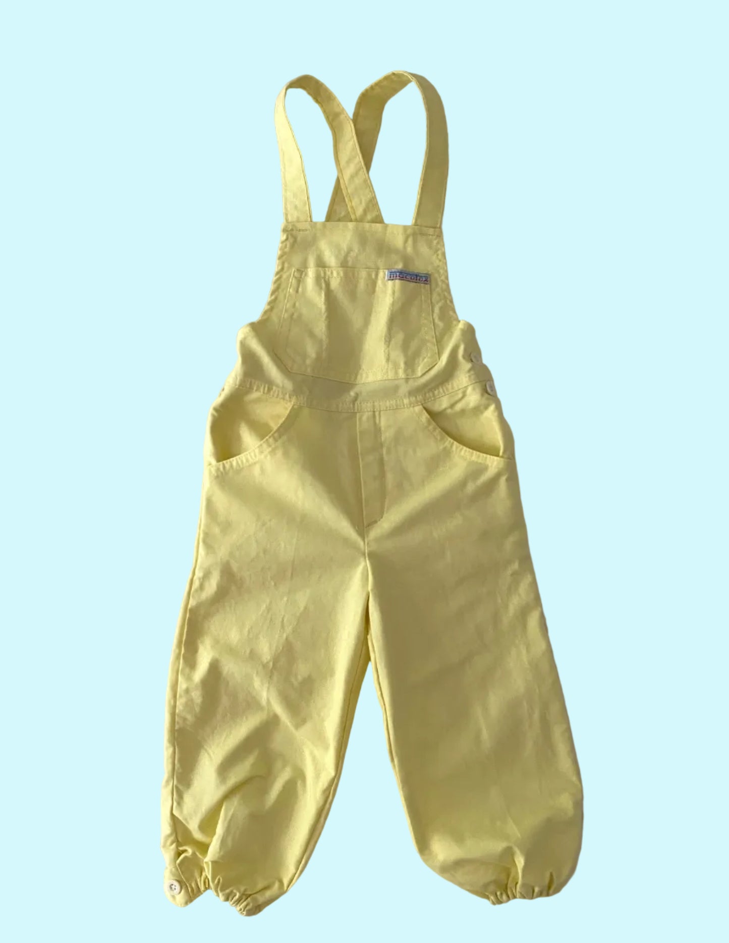 Yellow bib overalls on a textured white surface