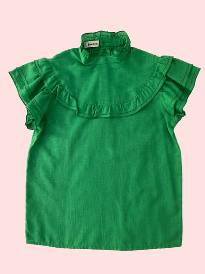 Green blouse with ruffled collar on a pink background