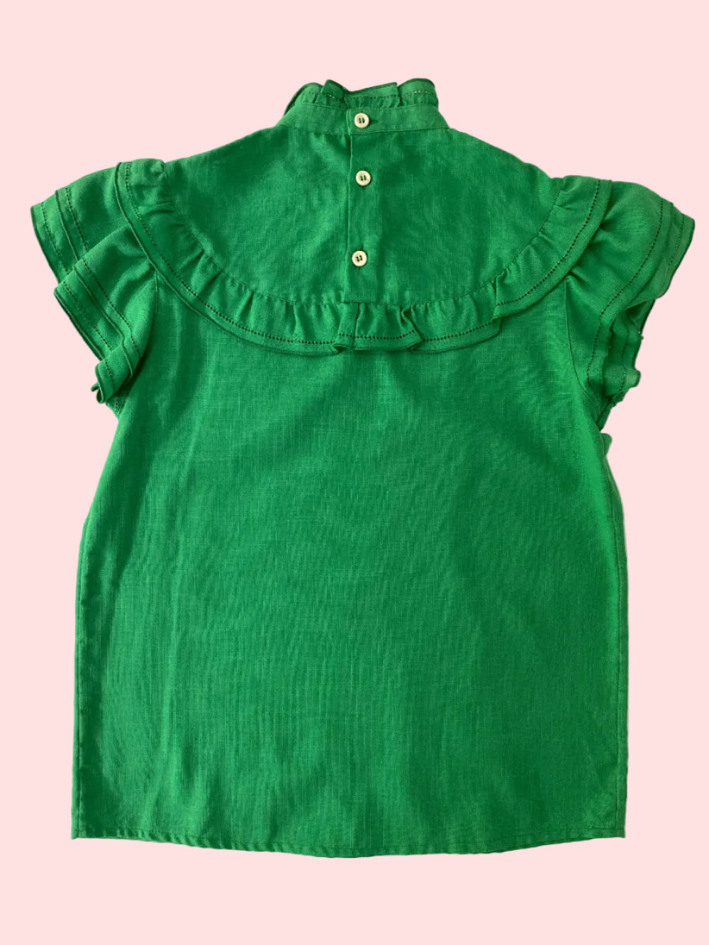 Green blouse with ruffled collar on a white textured surface