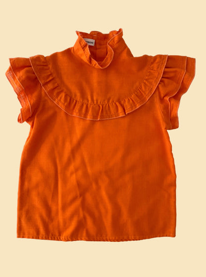 Orange blouse with ruffled collar on a beige background