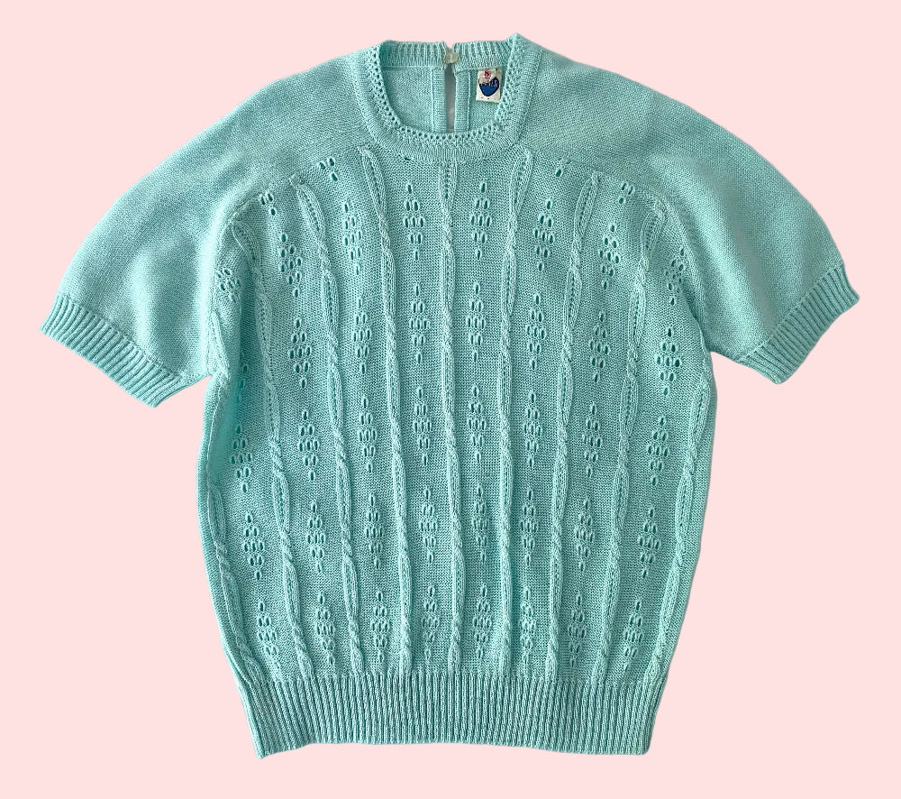 Light blue short-sleeve sweater on a textured white background