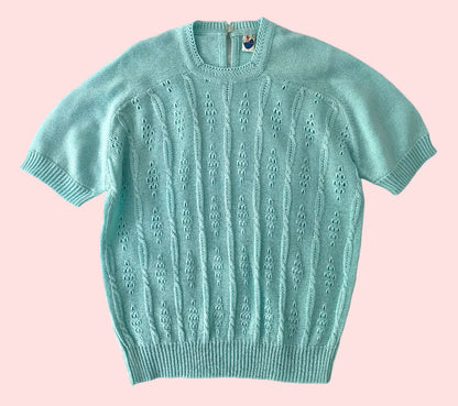 Light blue short-sleeve sweater on a textured white background