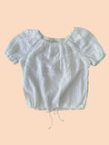 White blouse with lace details on a wooden surface