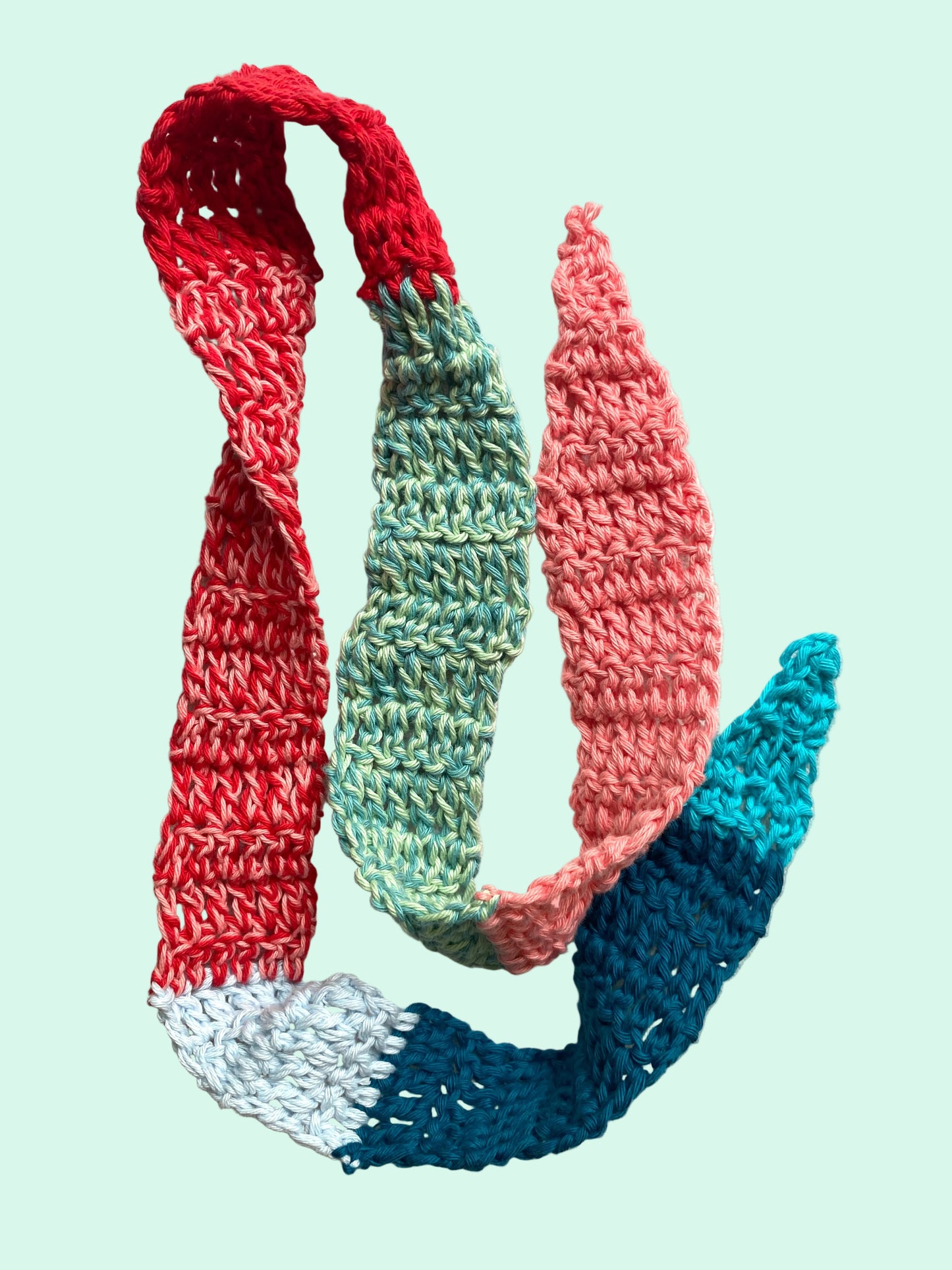 Colorful knitted scarf with red, green, and blue sections on a light background