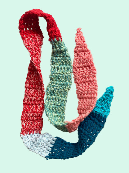 Colorful knitted scarf with red, green, and blue sections on a light background