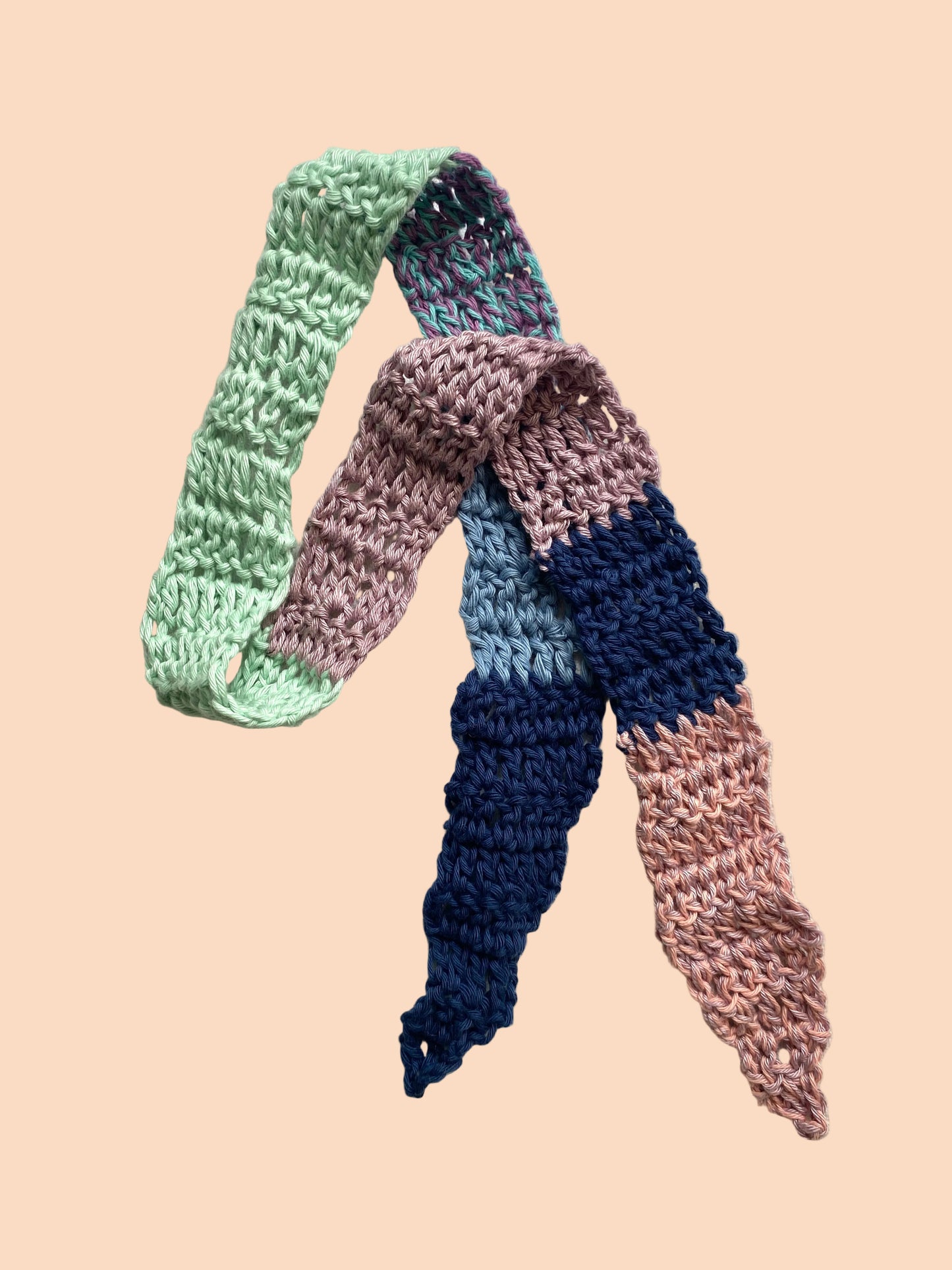 Two crocheted scarves in pastel colors on a light background